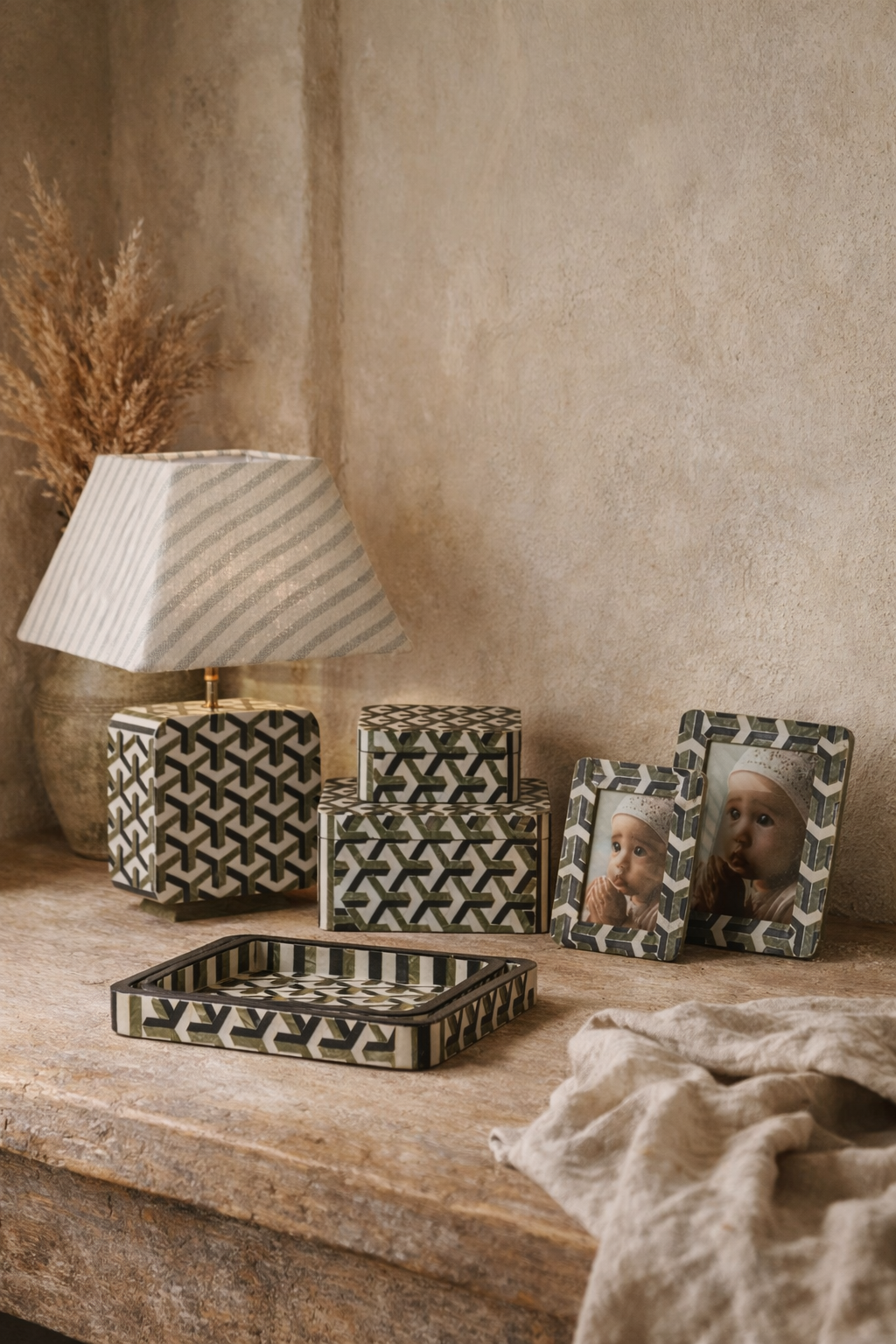 Decorative items including a lamp, boxes, trays, and picture frames on a wooden surface with a beige wall background.